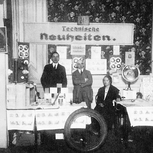A historical trade show booth titled “Technical Innovations,” featuring technical products on display and several people from 1920s.