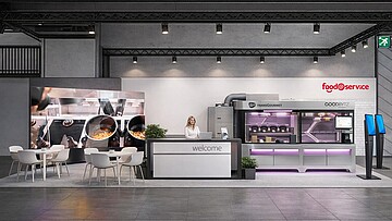 Messestand in modernem, offenen Design. In der Mitte steht ein Empfangstresen mit der Aufschrift „welcome“, hinter dem eine Person steht. Links befinden sich mehrere kleine Tische mit weißen Stühlen sowie eine große Wand mit einem Küchenmotiv. Rechts sind professionelle Gastronomiegeräte und Automaten mit lila Beleuchtung zu sehen, darüber das Logo „food@service“. Daneben stehen zwei blaue Informations- oder Bestellterminals.