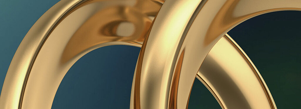 Nahaufnahme von ineinander verschlungenen goldenen Ringen mit glänzender Oberfläche auf dunklem Hintergrund.