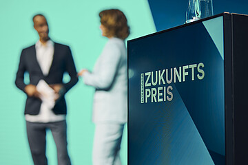 Verleihung des INTERNORGA Zukunftspreises auf der Bühne Podium mit dem Schriftzug „Zukunftspreis“ und zwei Personen im Hintergrund während einer Bühnensituation auf der INTERNORGA.
